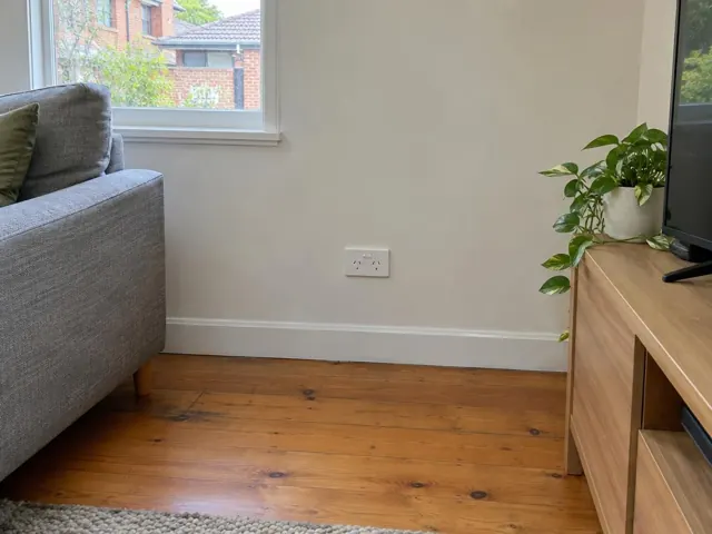 Wall power point in a painted living room beside a window, sofa and TV cabinet in Newcastle