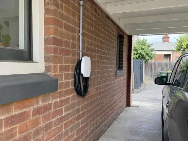 EV charger mounted on a brick wall under a covered driveway in The Hill
