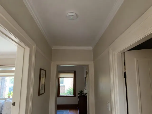 Ceiling smoke alarm in a painted hallway with timber trim and doorways in Bar Beach